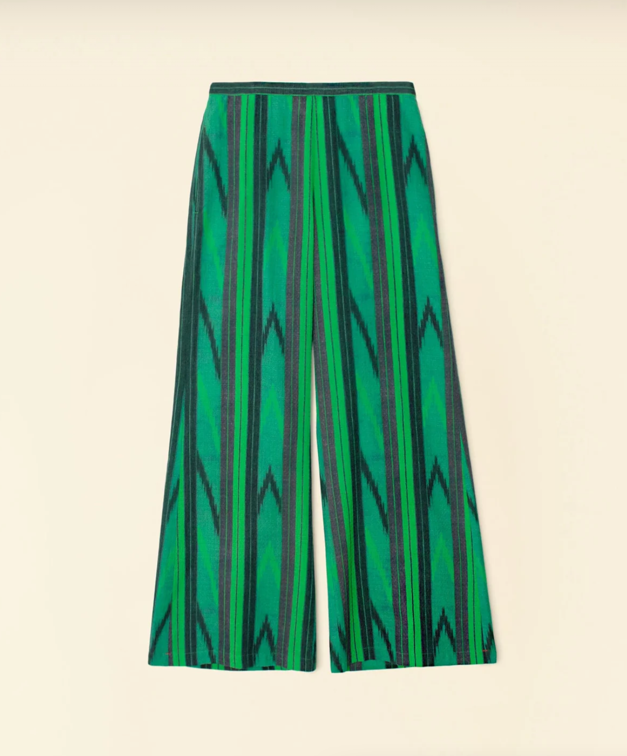 The Pippen Pant by Xirena is a pair of wide-leg pants showcasing a striking green and black zigzag pattern running vertically. Featuring an elasticized high waist for enhanced comfort, these pants have a relaxed fit with subtly flared bottoms. Made from soft ikat stripe cotton dobby, the base fabric is plain and light-colored.