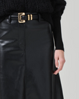 A person wearing the buttery supple Cassia Leather Skirt in black from Citizens Of Humanity/AGOLDE, accessorized with a black belt featuring a gold buckle. The high-rise skirt is paired with a black knitted sweater, and the background is plain light gray.