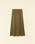 The Sela Skirt by Xirena, a midi-length, olive-green piece with a straight cut, is shown against a plain beige background. Made of luxurious silk charmeuse and featuring an elastic waistband, this slip-on skirt exudes effortless elegance.