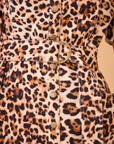 Take a closer look at the Robinson Dress by Hunter Bell NYC, an essential addition to your wardrobe with its striking leopard print fabric. This eye-catching piece is designed with a belt adorned with a round metal buckle and cascading buttons down the front, showcasing a vibrant mix of brown, black, and beige hues reminiscent of wild leopard spots.