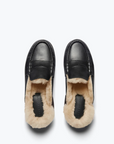 From an overhead perspective, the TEMI SHEARLING PENNY LOAFER MULE by Freda Salvador showcases a sleek, polished exterior made from Italian leather in black and a cozy interior lined with tan ethically sourced shearling.