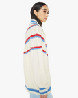 A person with long dark hair wears the oversized "The Mock Neck Button Cardigan" by Mother. The sweater is in a cozy and casual cream alpaca cotton blend with a slouchy fit, featuring red and blue stripes, as they stand sideways against a white background.