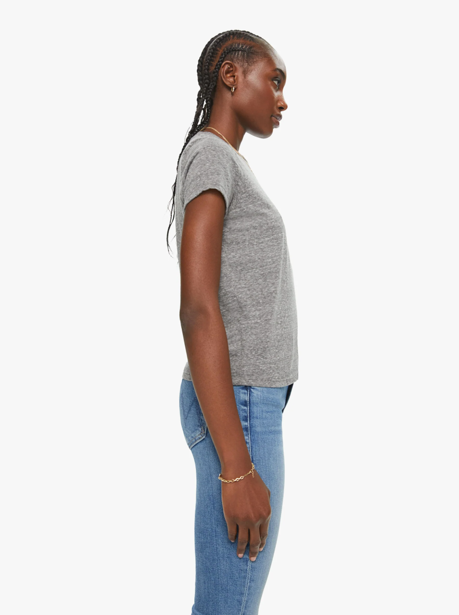 A person with braided hair is wearing The Lil Goodie Goodie Tee by Mother, a soft crewneck gray T-shirt, paired with vintage-looking blue jeans while standing in profile against a plain white background.