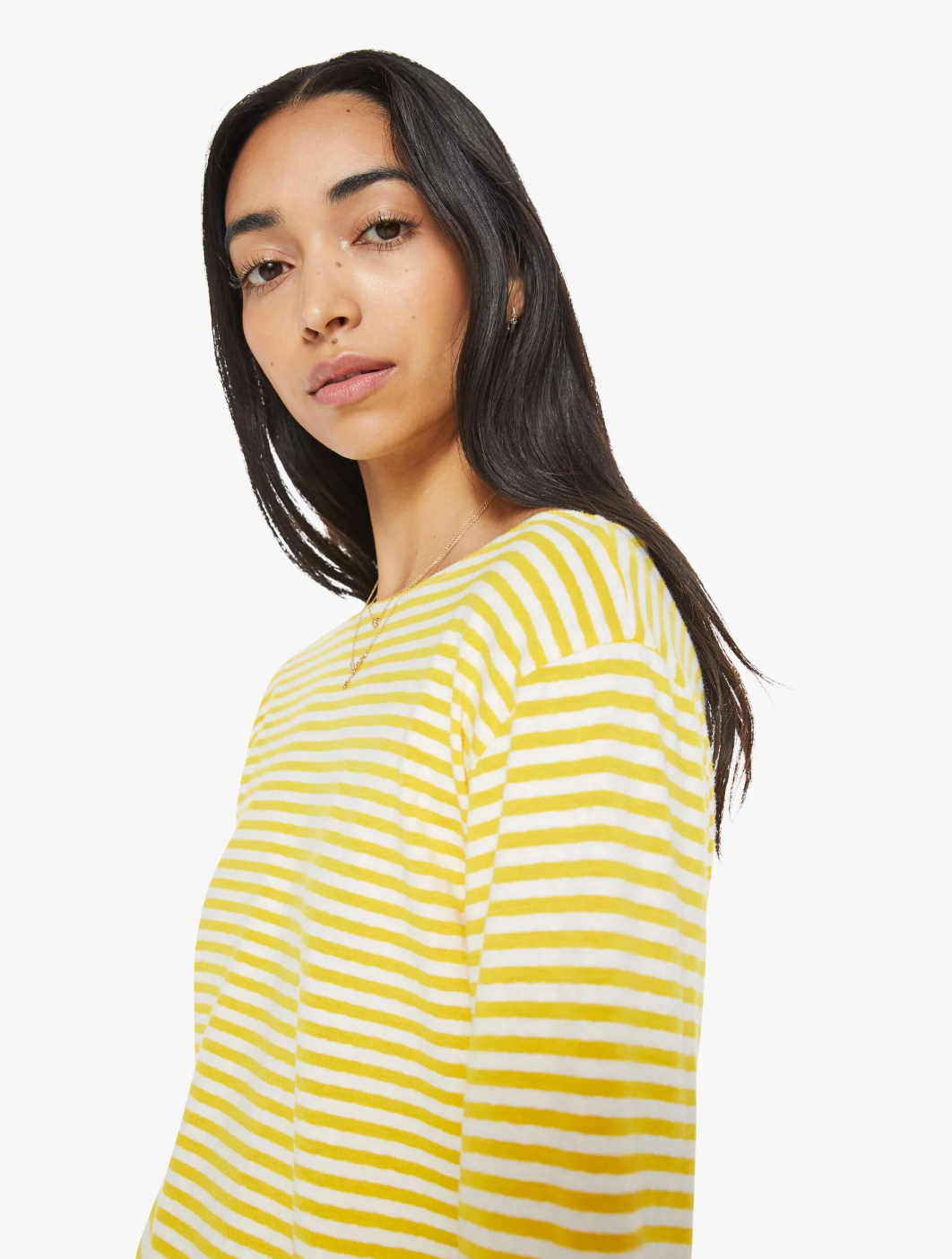 A person with long dark hair is wearing The Skipper Bell LS Tee by Mother, featuring yellow and white horizontal stripes and long sleeves, gazing at the camera with a neutral expression against a white background.