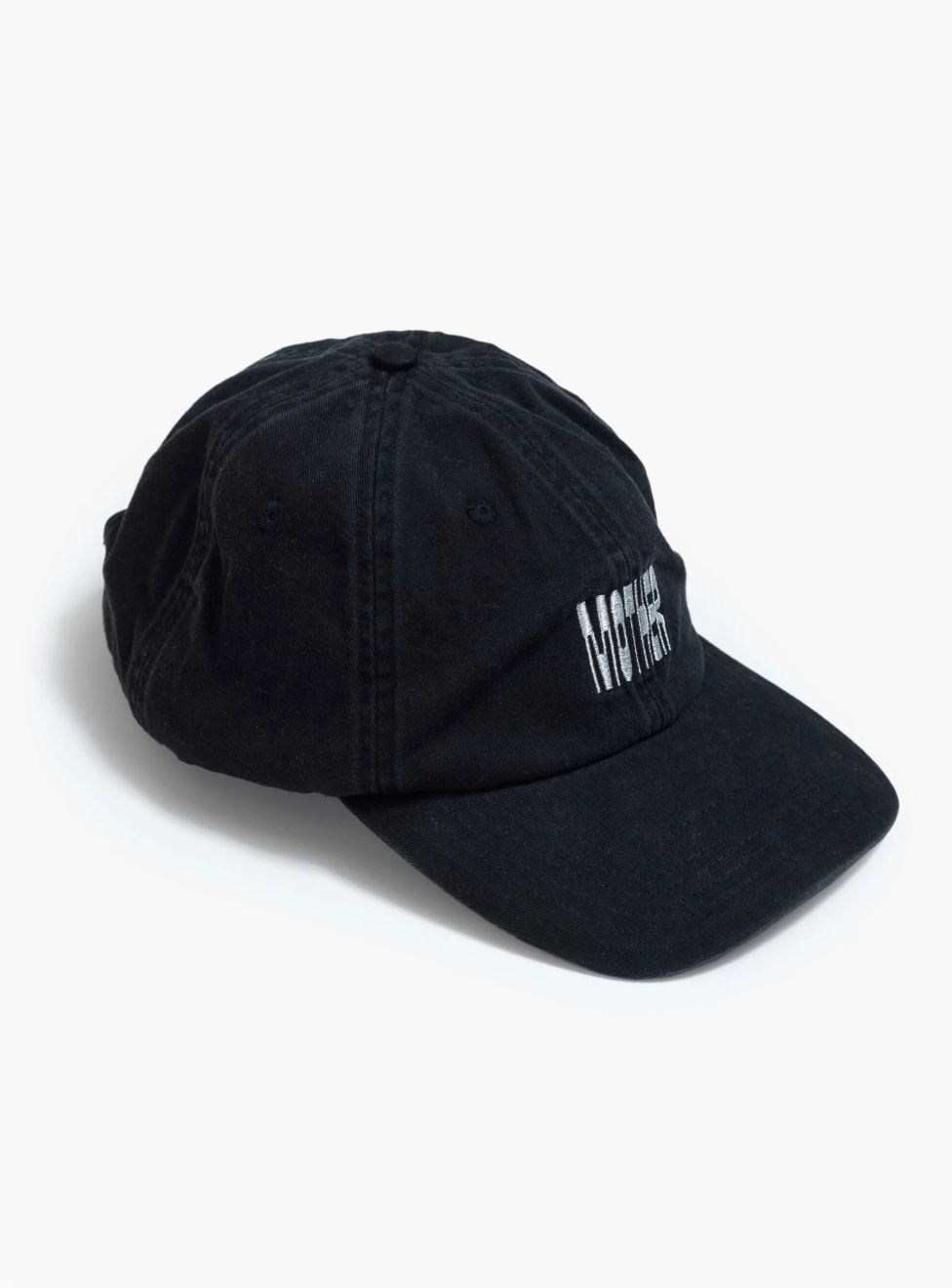 A slightly worn black cotton dad hat from the brand Mother, featuring "Mother" embroidered in white on the front, rests on a pristine white background. Product Name: Hats Off.