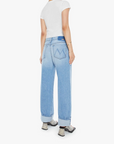 Rear view of a person in Mother Lil Dodger button Hover Cuff jeans with a loose fit and faded blue detail, styled with a plain white t-shirt and snakeskin-patterned shoes. Ideal for petite body types seeking stylish comfort in SUPERIOR denim. Arms are relaxed by their sides.