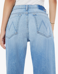 The rear view showcases a person in light blue high-waisted Mother denim jeans, ideal for petite figures, with "W" stitching on the back pockets. A white shirt is tucked in, and the outfit is elegantly finished with a Lil Dodger button Hover Cuff gold bracelet.