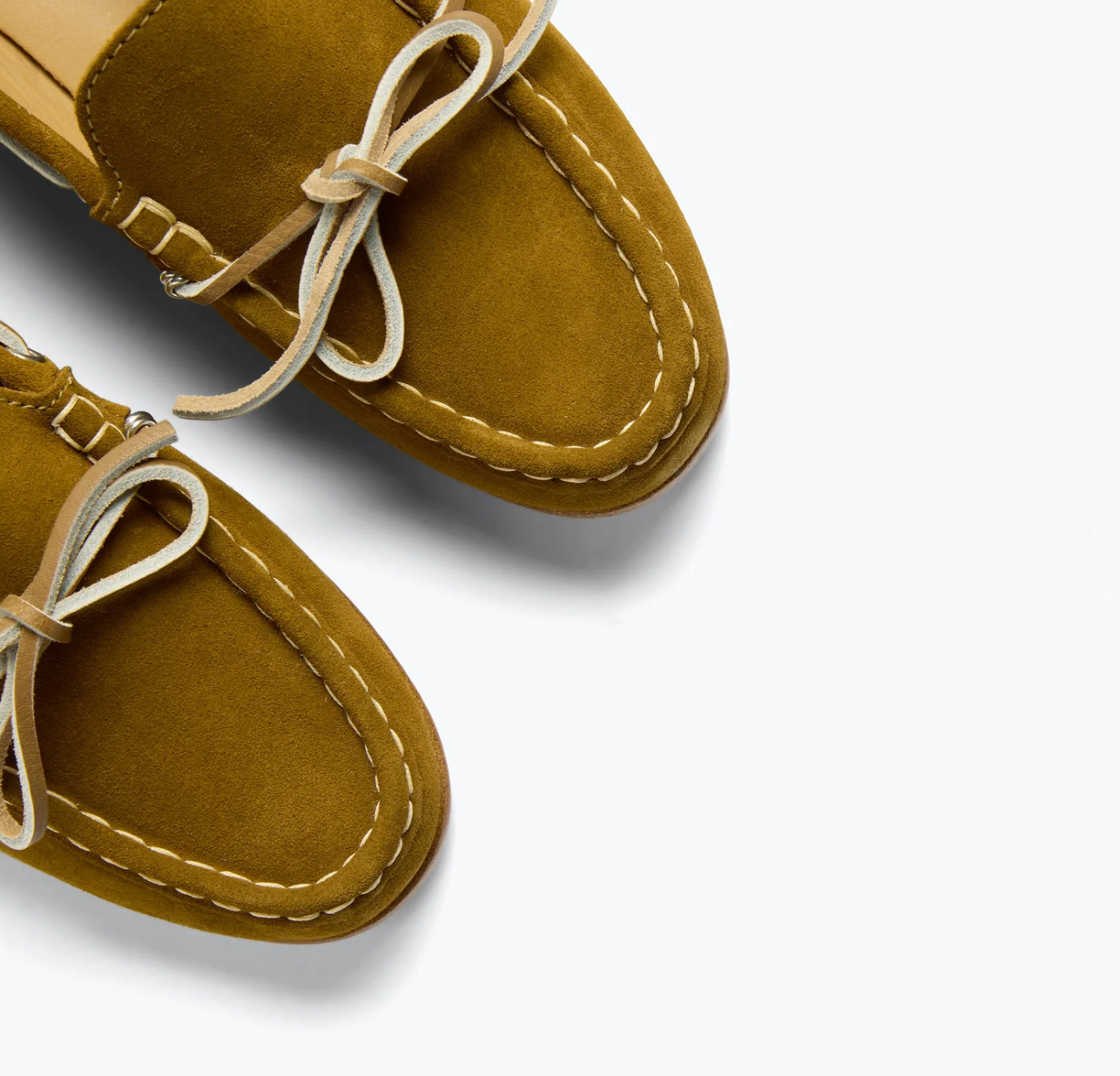 A close-up of Freda Salvador's MORGAN Loafer in mustard yellow Italian suede, featuring white stitching and tied leather laces, set against a light gray background.