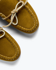 A close-up of Freda Salvador's MORGAN Loafer in mustard yellow Italian suede, featuring white stitching and tied leather laces, set against a light gray background.