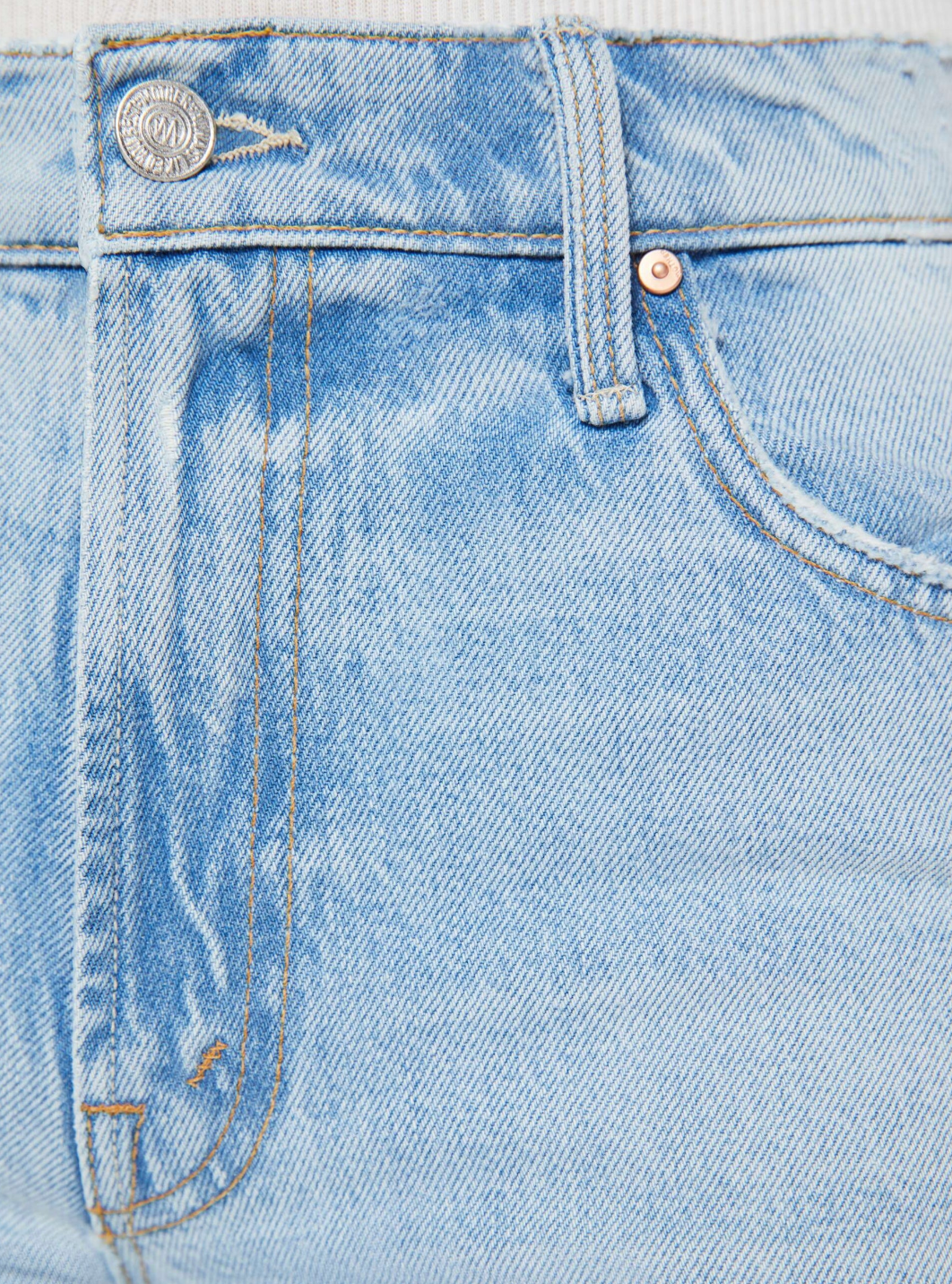 Close-up of The Spinner Zip Sneak by Mother: light blue, high-waisted jeans with a metallic button on the waistband, belt loops, detailed stitching on pocket and seams. Crafted from rigid denim, the fabric has a slightly worn texture.