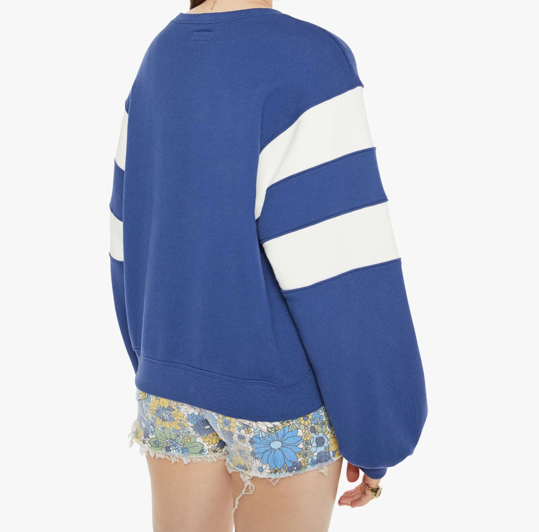 Styled in Mother’s The Drop Square Inset, a blue oversized sweatshirt with white striped sleeves and drop shoulders crafted from 100% cotton, they pair it with floral shorts featuring lace trim against a plain white background to display the chic ensemble's back.