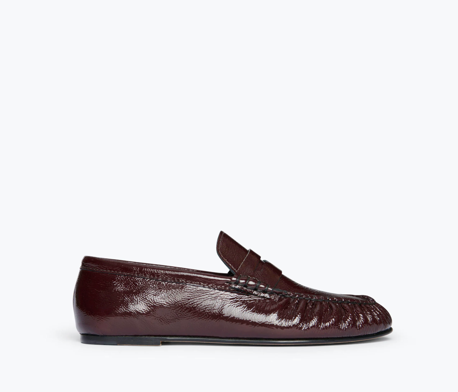 The Freda Salvador Sydney Crinkle Loafer is a dark brown Italian leather slip-on with a low heel, penny strap, and visible stitching. Shown from the side on a white background, it's perfect for effortless sophistication.