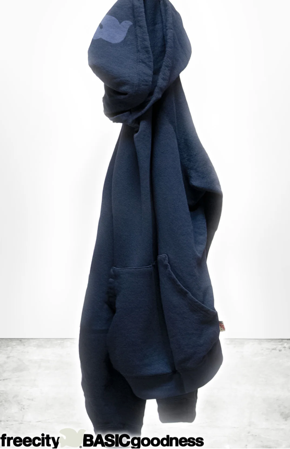 A navy blue BASIC GOODNESS HOODIE by Free City (sparrow, LLC), made in the USA, hangs on a hook against a plain white background. The text "freecity BASICgoodness" appears at the bottom of the image.