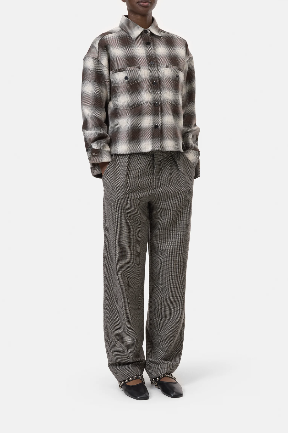 A person wears the CLOSED Cropped Front OS Shirt, a buttoned long-sleeve grey and brown checked cotton shirt with a chest pocket, paired with loose grey checked trousers and black pointed-toe chain-detail shoes against a white background.
