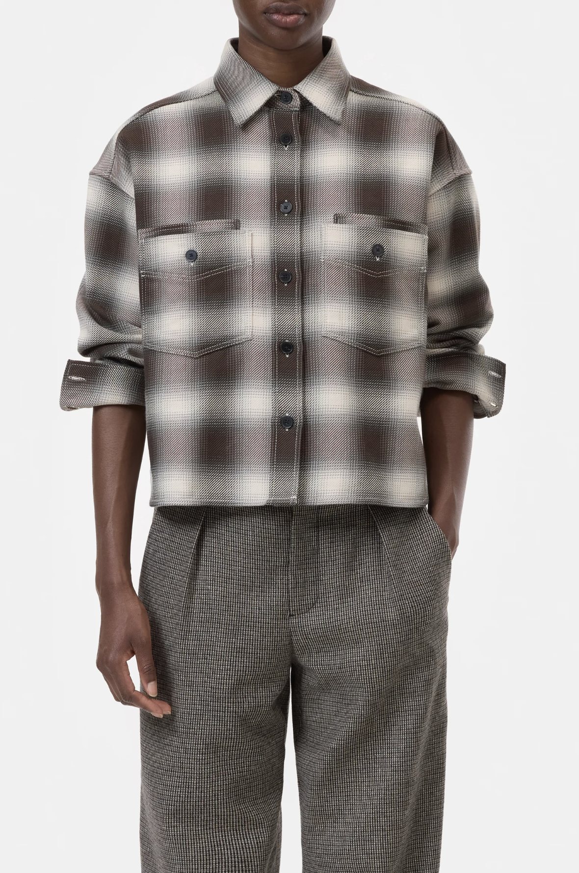 A person wears the CLOSED Cropped Front OS Shirt in brown and white checks with chest pockets and gray checked trousers, standing against a plain white background.