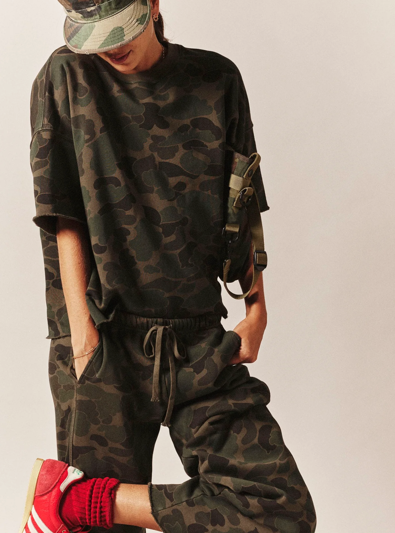 Renzo Sweatpant by Xirena, camo shirt and hat styled with red socks and sneakers, casual modern look.