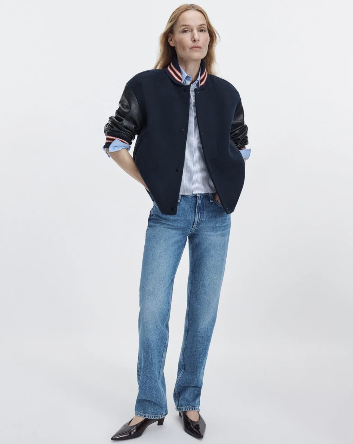 Scarlet Rag &amp; Bone varsity jacket with striped shirt, blue jeans, and black shoes in a casual outfit setting.
