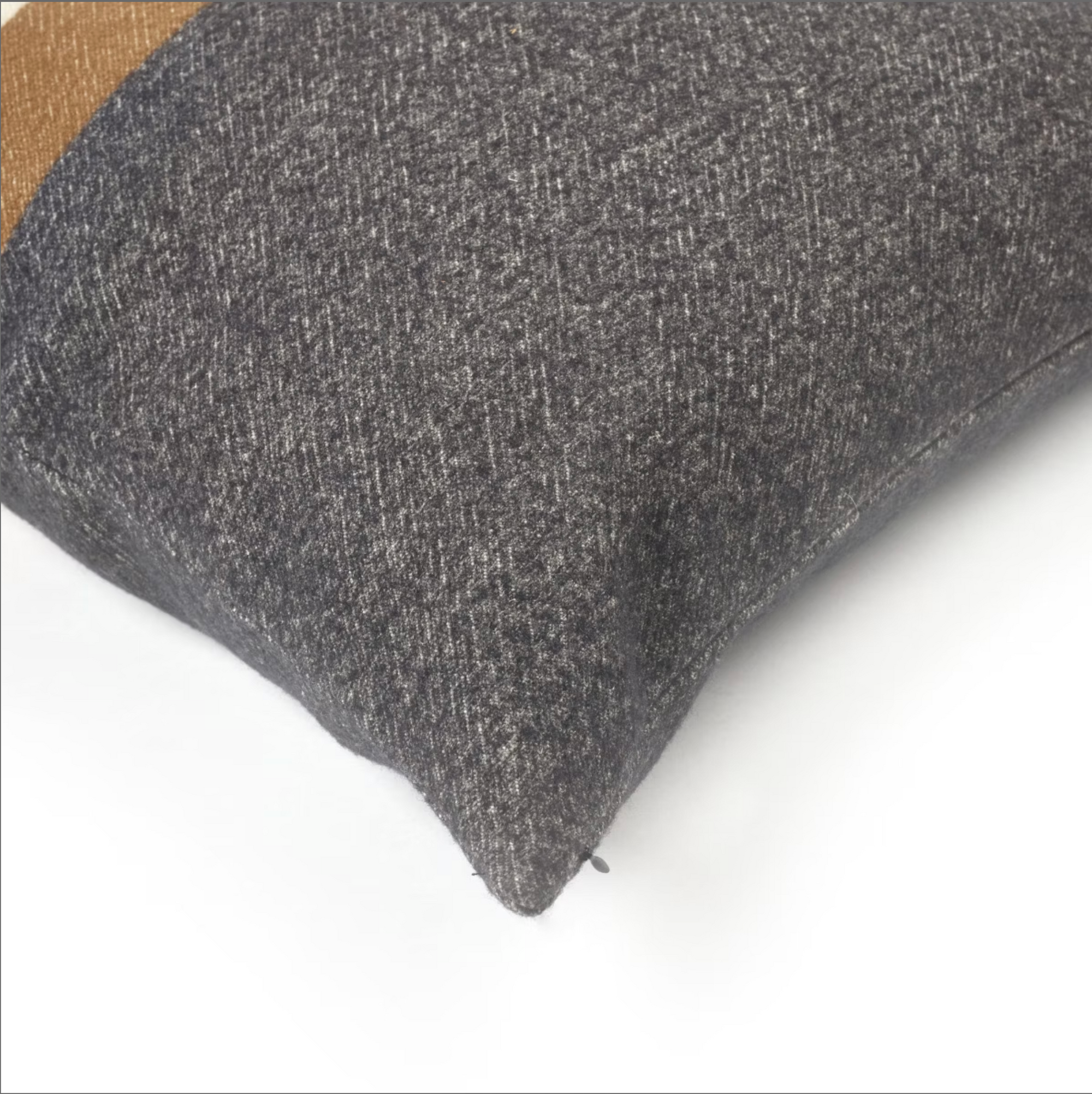 A close-up of the Libeco Home Nash Pillow, featuring dark gray fabric in rich arabica tones with a subtle texture, rests on a white surface. Its corner points bottom right, and a hint of brown fabric appears in the top left.
