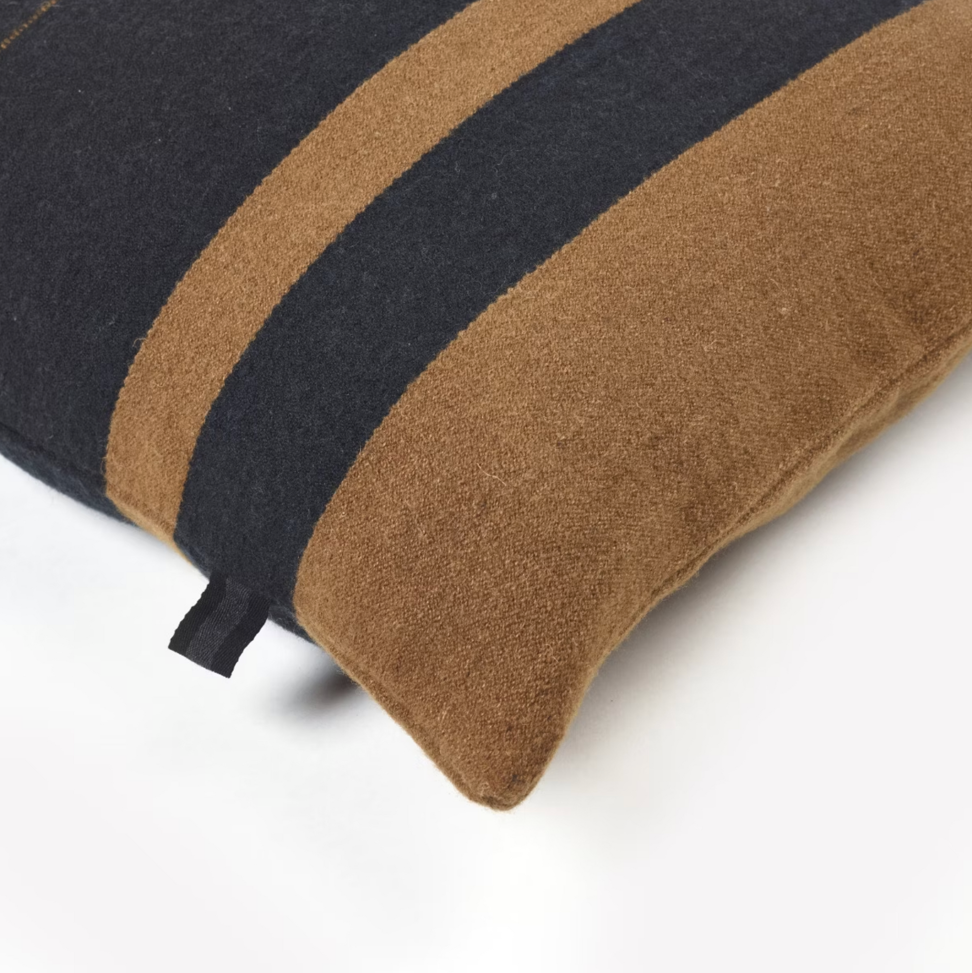 A close-up of the Libeco Home Oscar Pillow highlights its woolen texture and wide black and brown horizontal stripes on a white background.