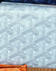 A close-up of light gray fabric with interlocking Y-shaped geometric patterns, bordered by orange and blue at the edges—ideal for making Faire’s designer-inspired Reusable Shopping Bags.