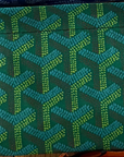 A green and blue geometric patterned Faire Reusable Shopping Bag, featuring an arrow-like design reminiscent of a designer beach bag, displayed on a wooden surface.