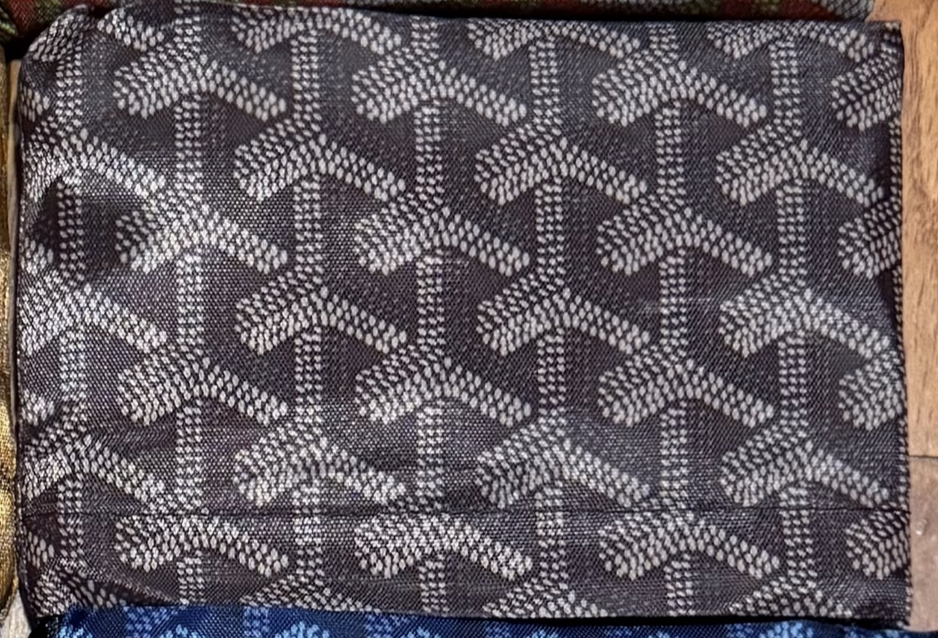 A close-up of textured fabric from Faire's Reusable Shopping Bags Assorted, featuring a repeating white chevron pattern on dark grey—designer-inspired and ideal for chic beach bags or eco-friendly shopping.