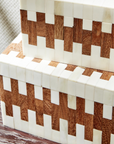 Two's Company JigSaw Covered Boxes, featuring a geometric pattern of alternating light and dark wood-like segments, stacked together on a mottled brown and white surface.