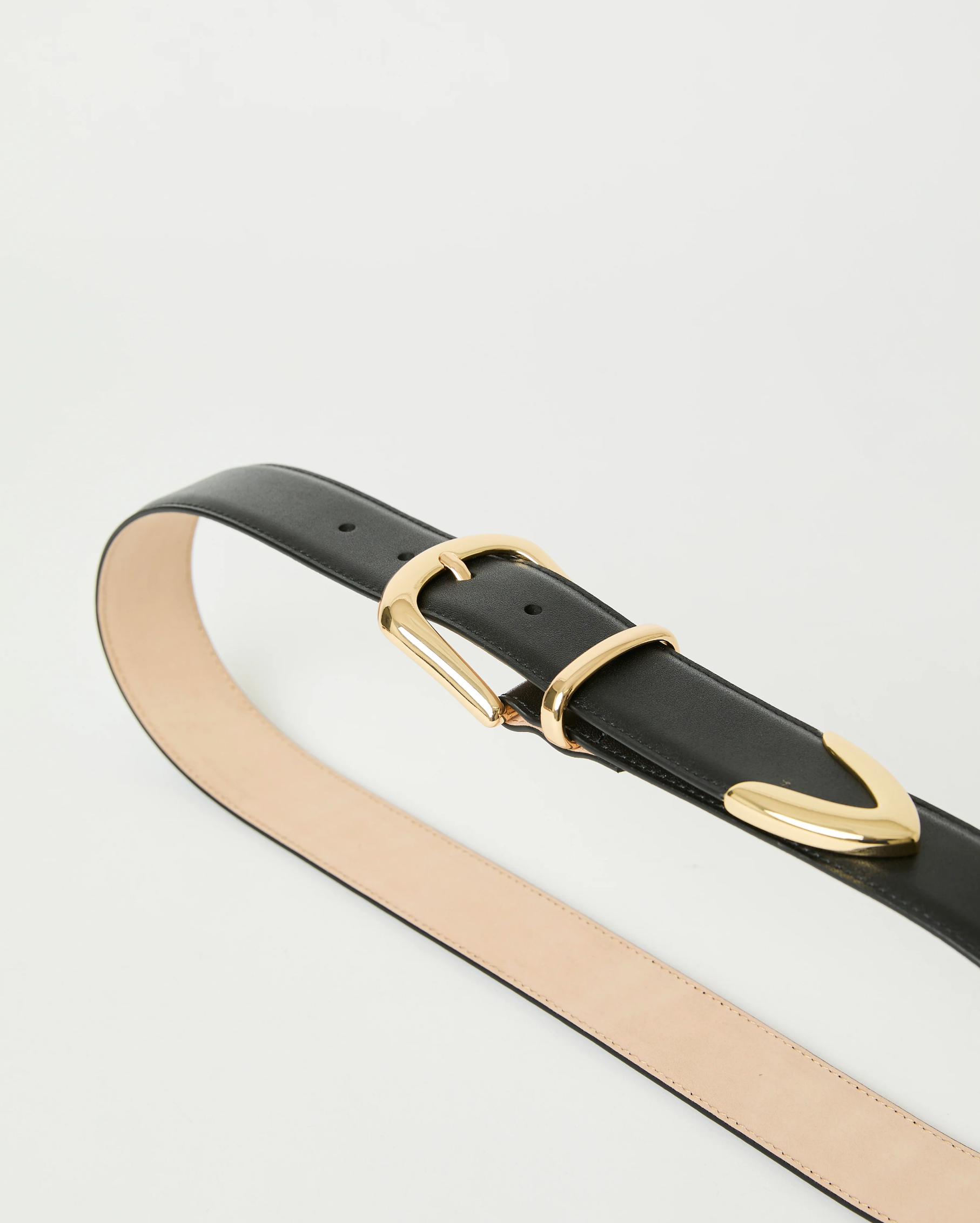 The Marc Belt by B-Low The Belt features black calfskin leather, gold-tone hardware with a matching gold loop, and a tan inner side, shown coiled on a white background.