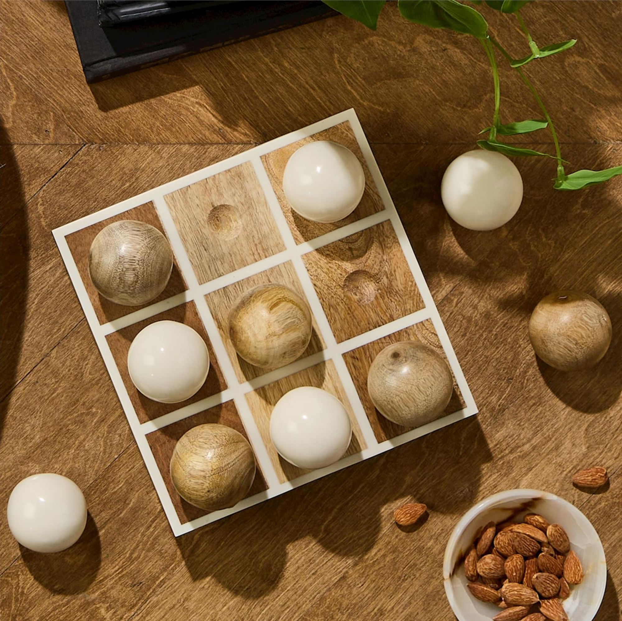 The Tic Tac Toe Game by Two's Company is a hand-crafted mango wood set with light and dark wooden spheres, ideal as unique decor for your game room.