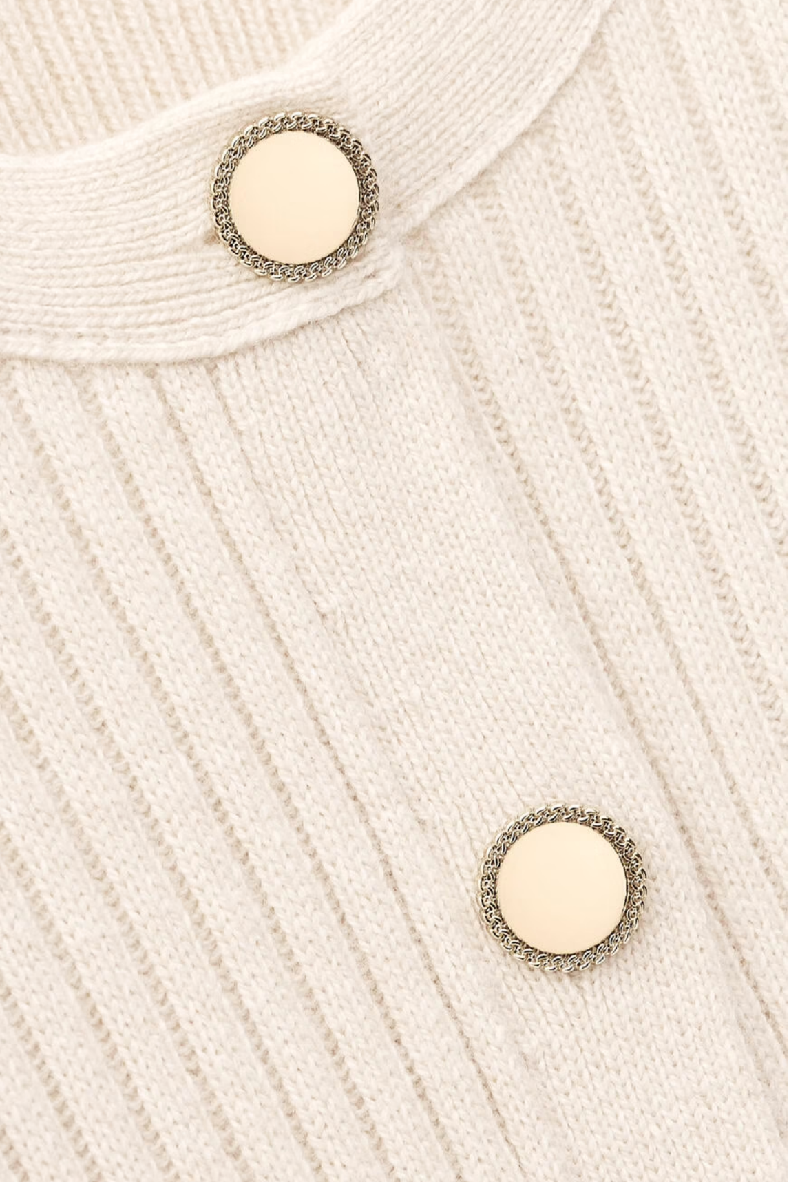 Close-up of the BA&SH Dress Anisa's cream-colored ribbed knit wool blend fabric, detailed with two round ivory buttons featuring decorative metallic edges.