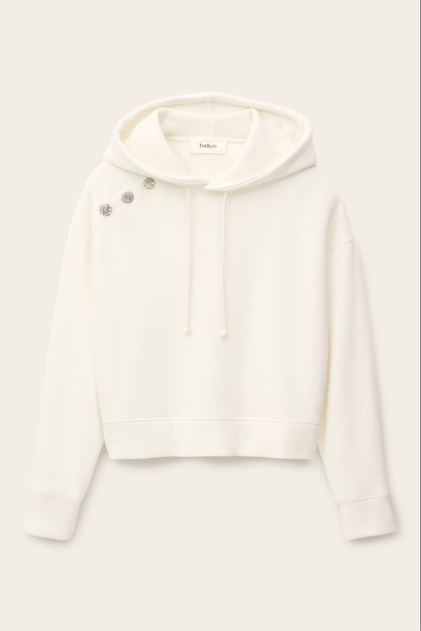 The BA&SH Sweatshirt Didi is a white, long-sleeve hooded sweatshirt with drawstrings and three silver brooches on the left shoulder near the hood, made from soft, easy-care polyester cotton.