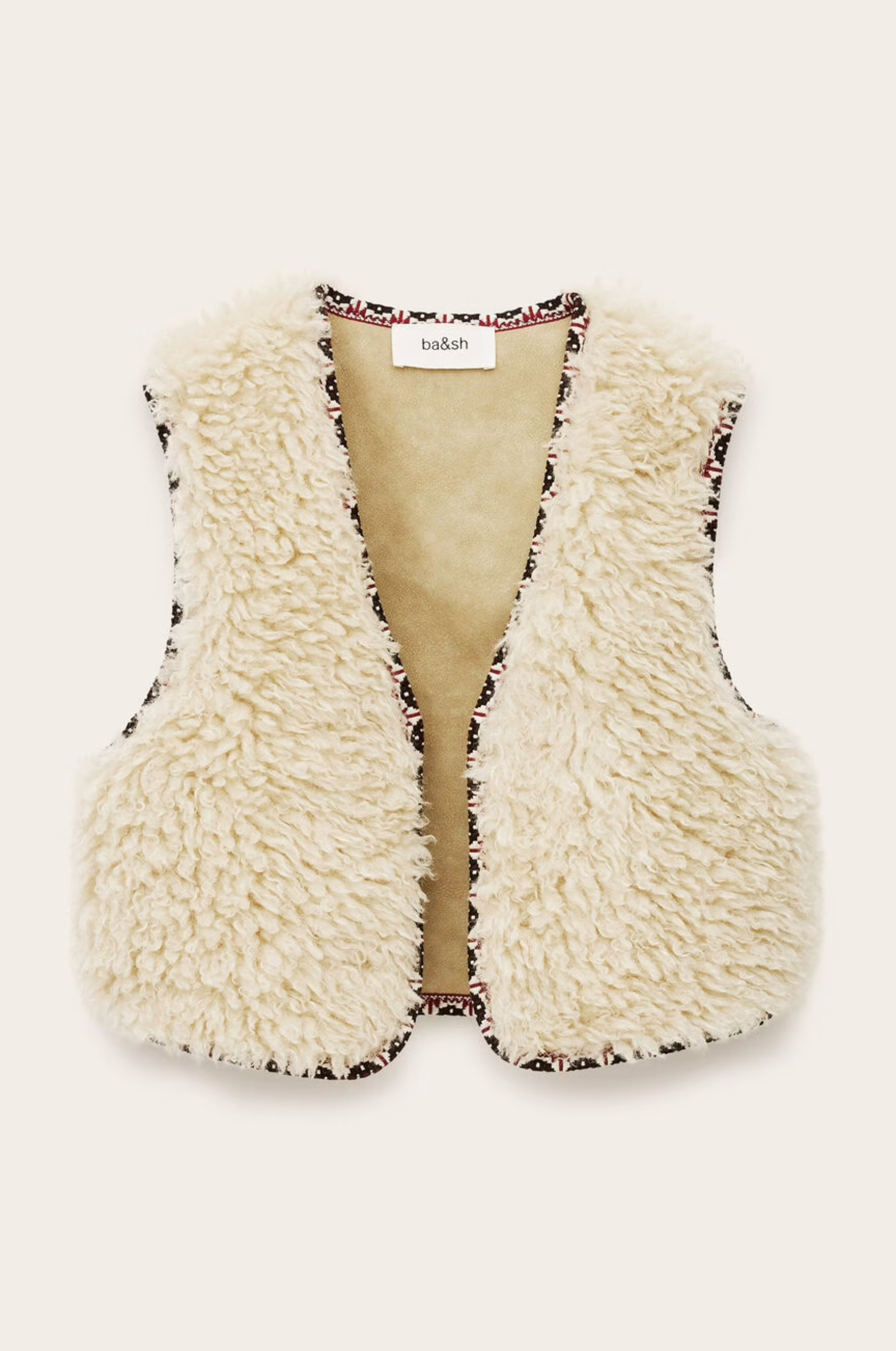 The BA&SH Jacket Celton is a sleeveless, cream faux shearling vest with fluffy texture and patterned edge trim, made from washable polyester and shown against a plain light background.