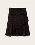The Skirt Rino by BA&SH is a black, knee-length polyester skirt with a ruched waistband and diagonal layered ruffles across the front and hem, shown against a plain light background.