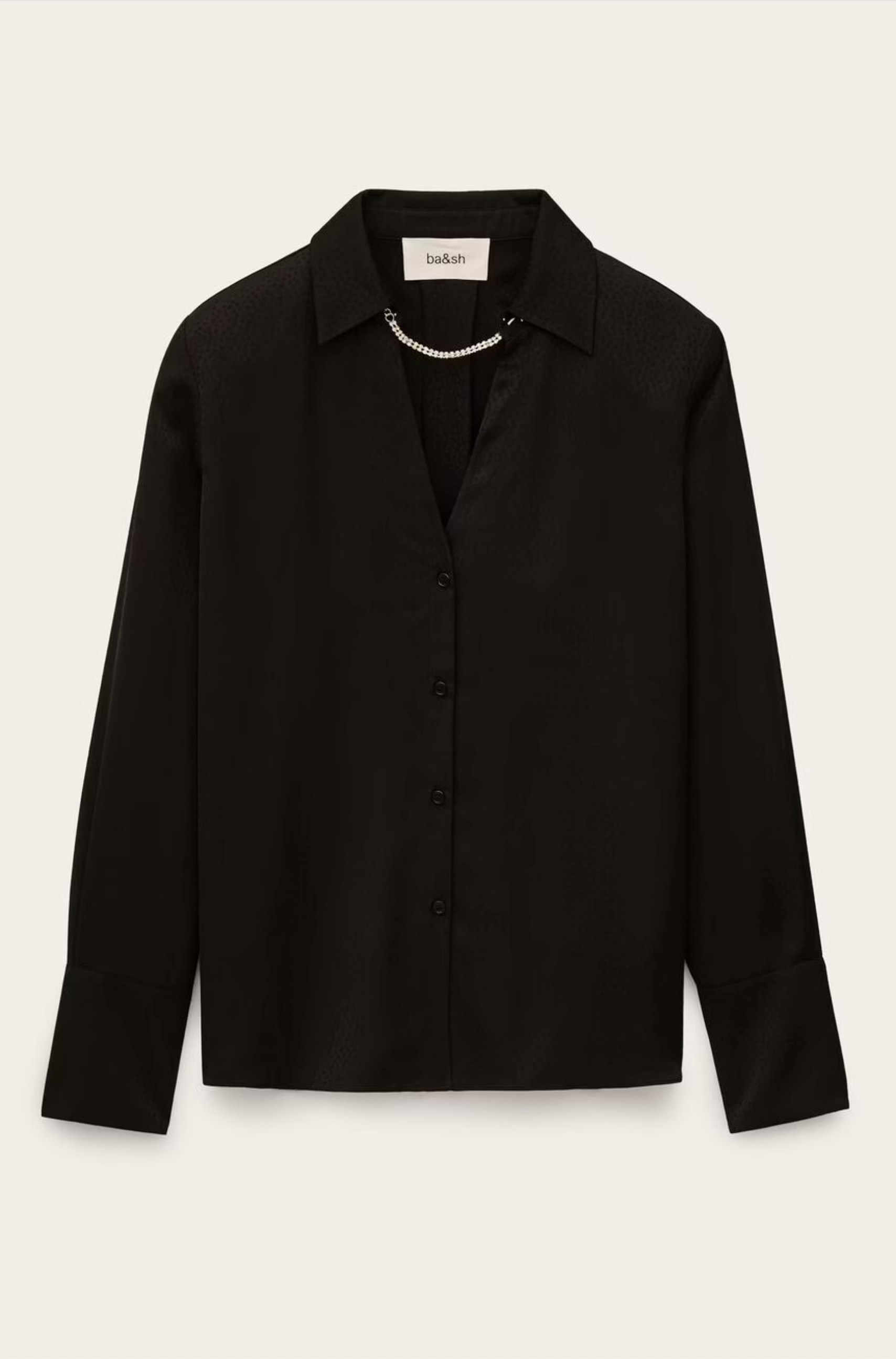 The BA&SH Shirt Itsey is a long-sleeve black button-up blouse with loose-fitting shoulders, a collar, and a subtle sheen, styled with a delicate pearl necklace draped across the collar.
