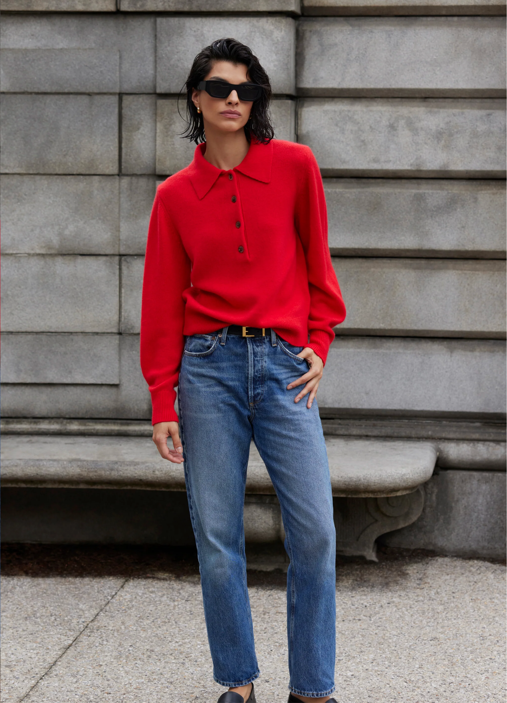 A woman in a Sold Out NYC Cashmere Polo and jeans.