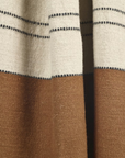 A close-up of the Foundry Throw by Libeco Home shows off-white fabric with black dashed lines above solid brown, featuring a soft, textured weave and stonewashed finish for lightweight comfort.