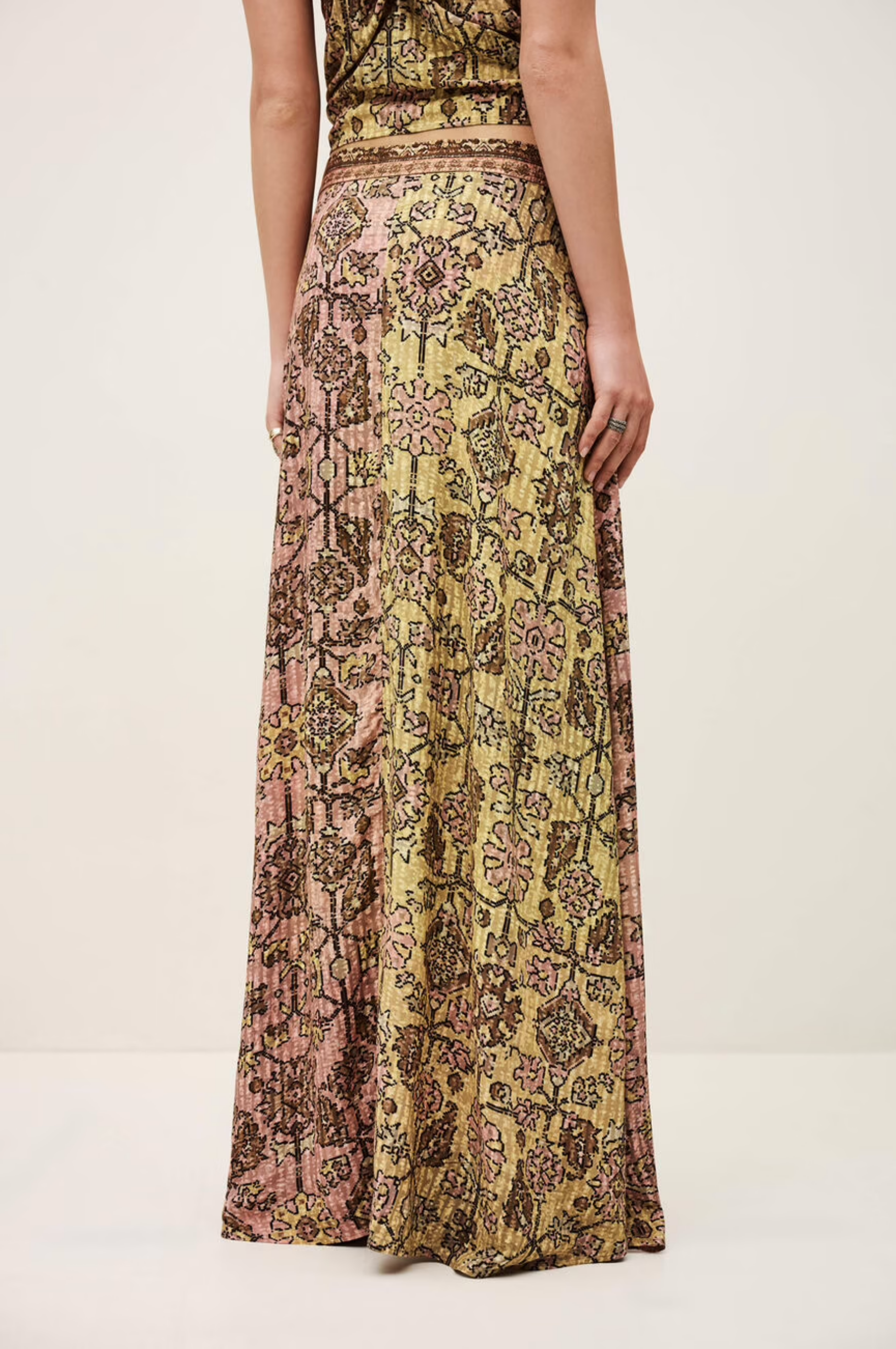 A person shown from the waist down wears the BA&SH Skirt Pario, a high-waisted, flared midi skirt with a pink and yellow floral pattern, against a plain background.