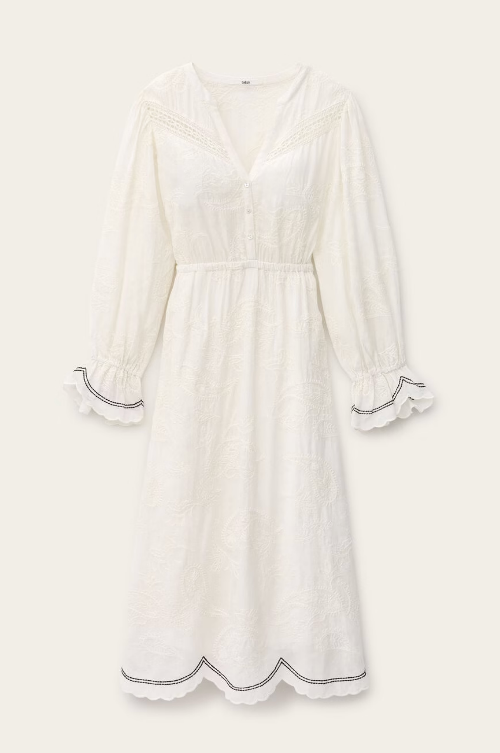 The BA&SH Dress Prisco is a long-sleeved, white dress with an elasticated waist, V-neck, button-down front, scalloped edges on cuffs and hem, subtle embroidery, and lace trim for an elegant touch.