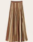 The Rima Skirt by BA&SH is a long maxi knit skirt with vertical brown, beige, and cream stripes, made from 100% viscose. It features a fitted waistband and flared silhouette for an elegant, flowing look.