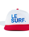 The Le Surf Vintage Lesure Icon Cap by Ping Pong Surf Club features a white crown, red brim and trim, plus bold blue "LE SURF." embroidery on the front for classic coastal style.