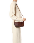 Jerome Dreyfuss Bobi Small Bag in brown with braided leather chain, held by person in an ivory sweater.