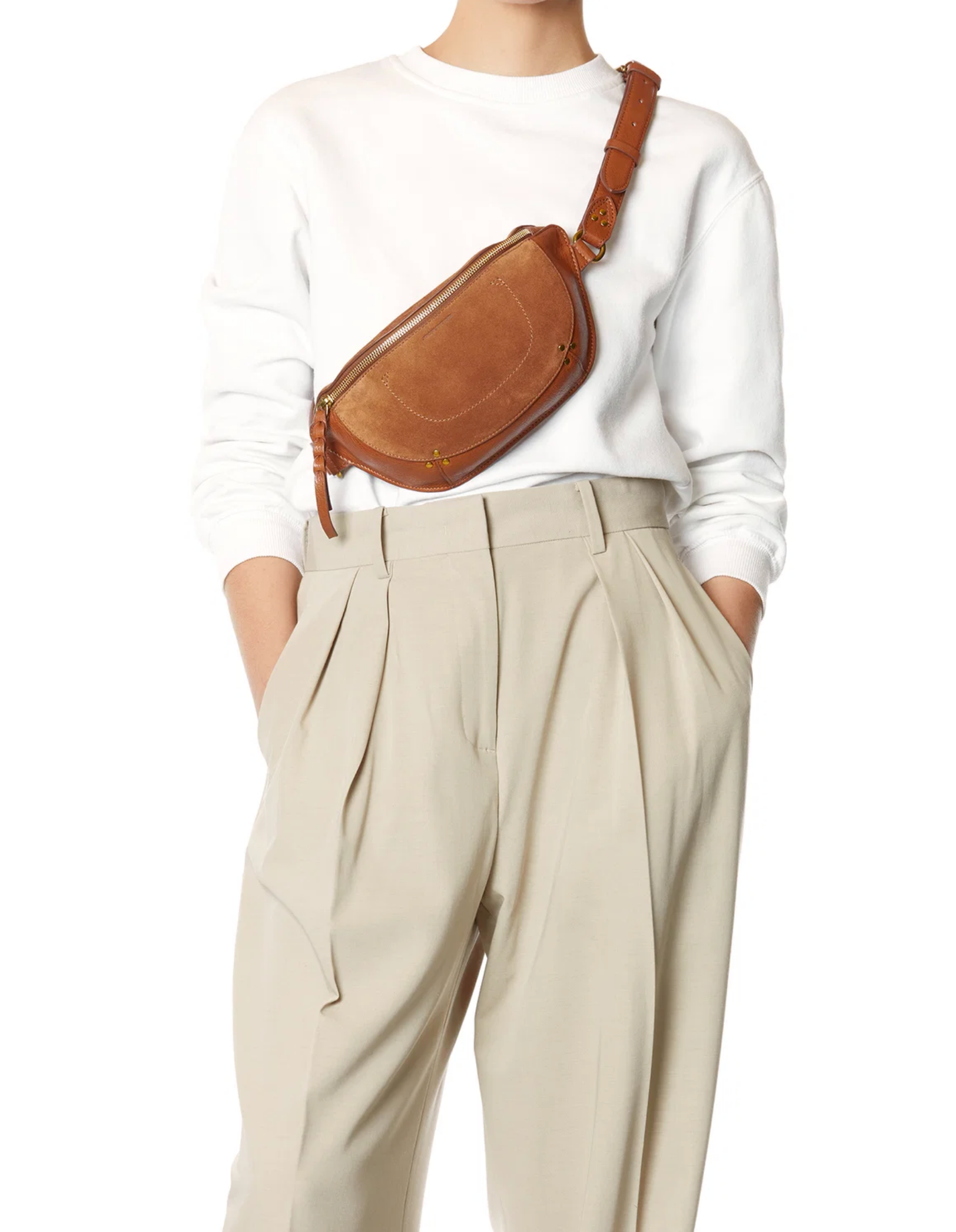 Jerome Dreyfuss Lino Banane bag styled with a white sweater and beige pleated pants, hands in pockets.