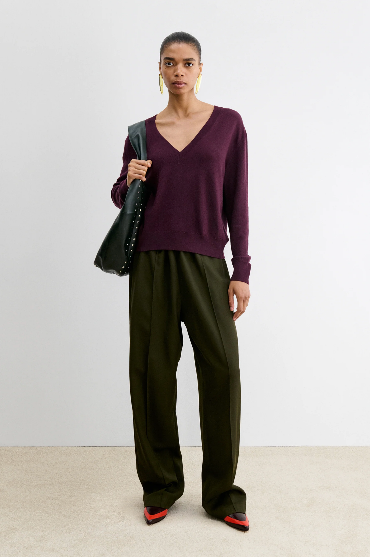 Slate Pullover by Rachel Comey styled with olive trousers and red shoes, set against a modern white wall backdrop.