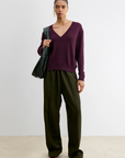 Slate Pullover by Rachel Comey styled with olive trousers and red shoes, set against a modern white wall backdrop.
