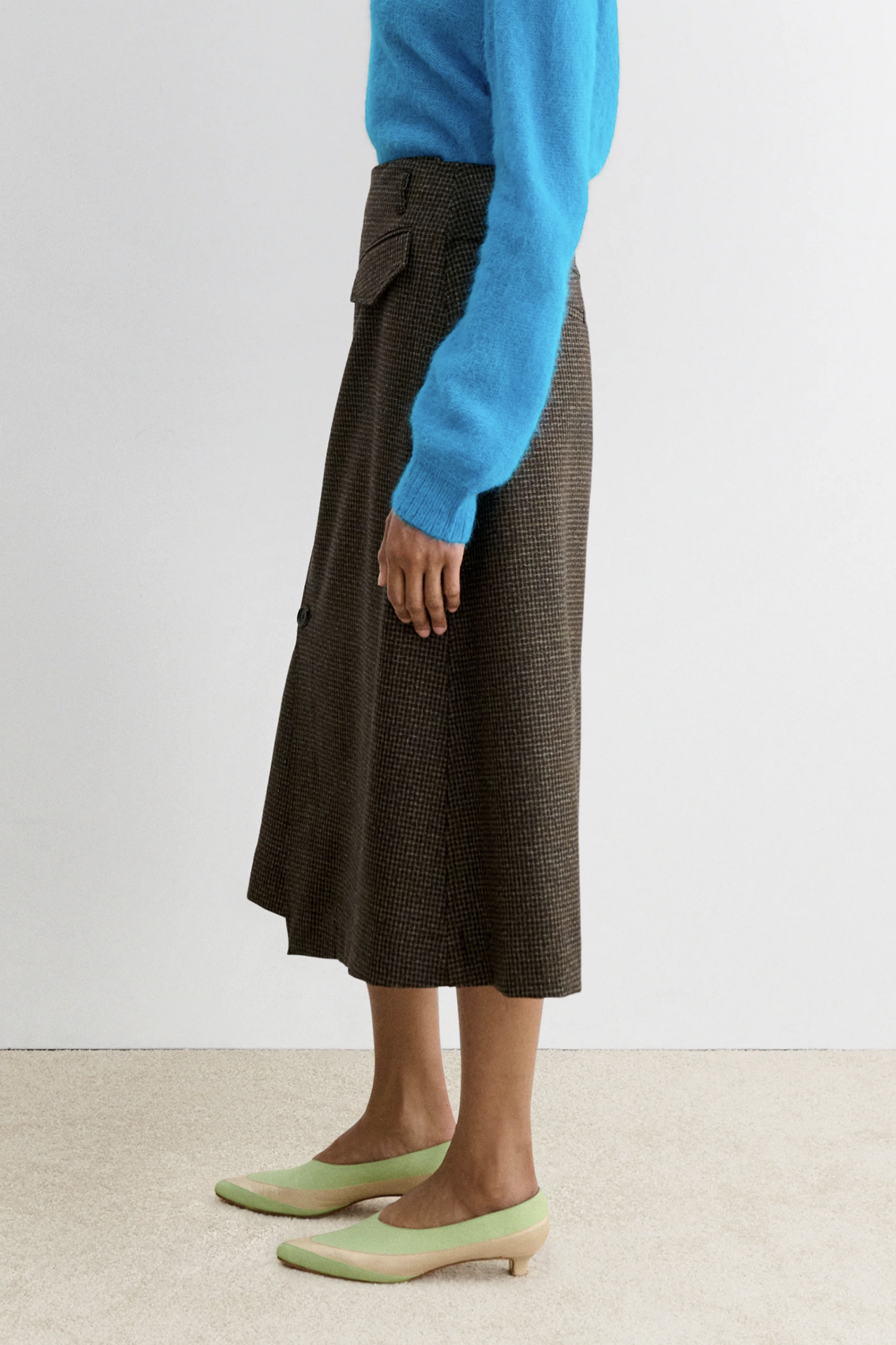 Rachel Comey Montrose Skirt styled with a blue sweater and light green heels on a beige carpet.