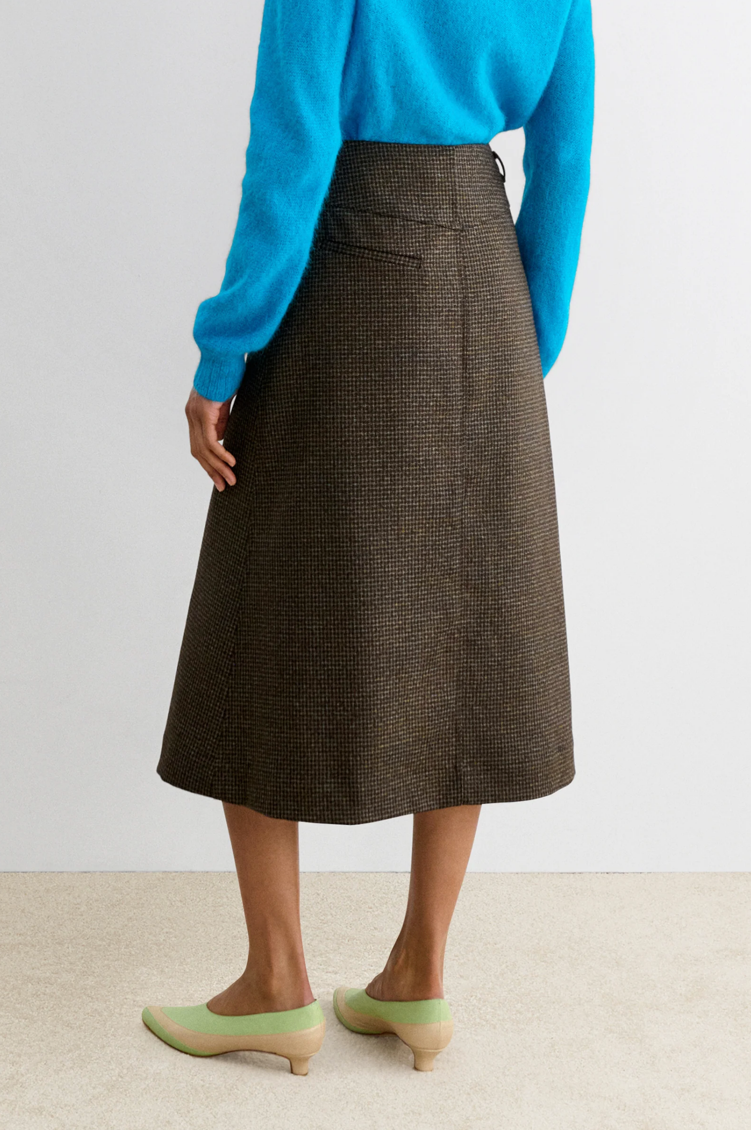 Rachel Comey Montrose Skirt in blue, styled with blue sweater and green low-heel shoes, back view.