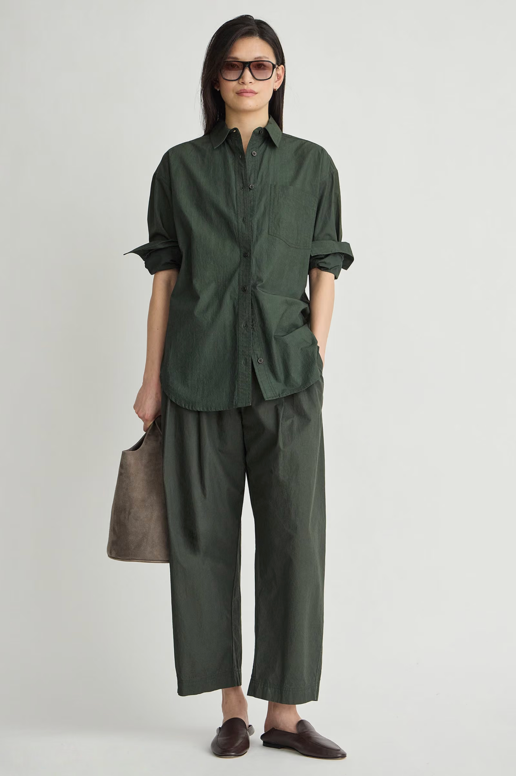 Oversized button down shirt by Apiece Apart styled with wide pants and gray bag in a casual, modern setting.