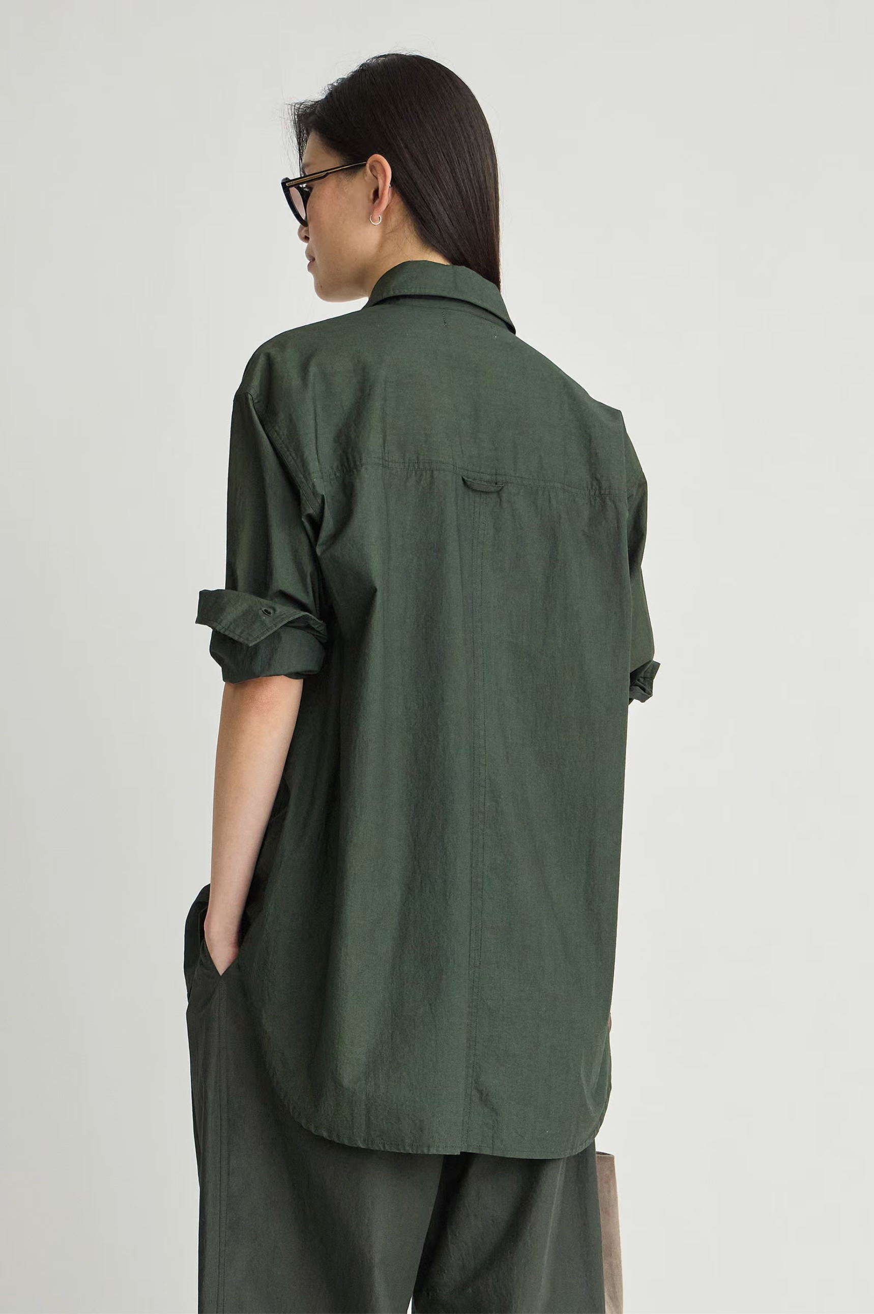 Dark green organic cotton Apiece Apart oversized button down, shown from behind on person with glasses.