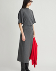 Luna Cinched Maxi dress by Apiece Apart styled with black boots, shown holding a red sweater against a plain backdrop.