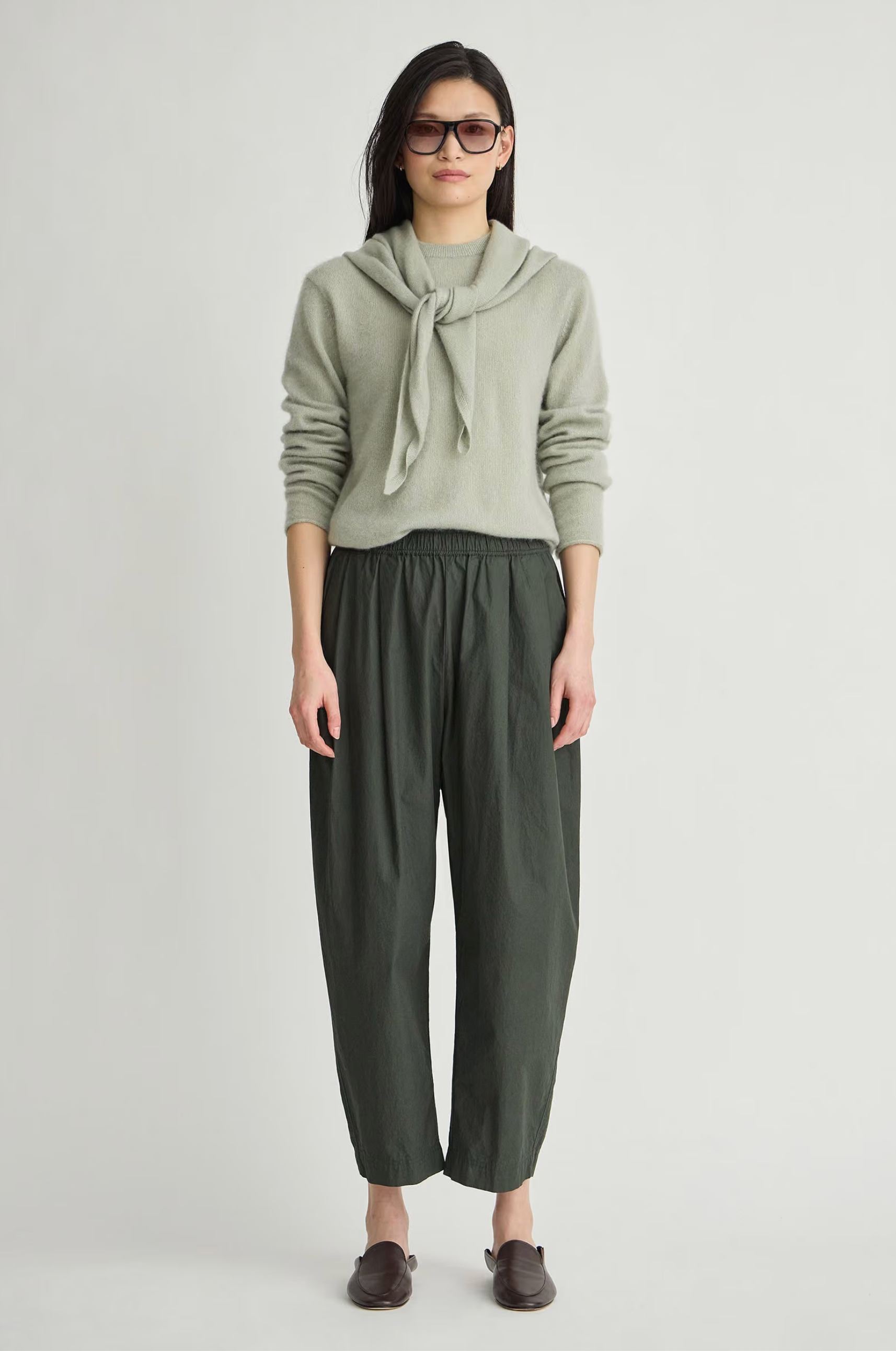 Apiece Apart Spa Pleat Pant in Rosin paired with an organic sweater, styled with brown shoes.